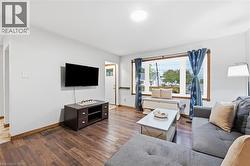 Living area featuring wood-finish flooring, a large window with wood trim, and light-toned walls - 