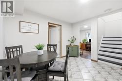 Tiled flooring throughout this bright space, featuring a white painted staircase with dark treads and an open doorway to another room - 