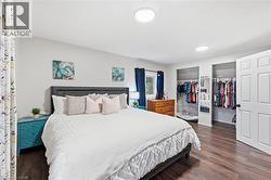 Bedroom featuring wood-finish flooring, a white paneled door, and two recessed clothing alcoves - 