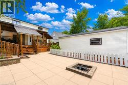 Expansive paved patio featuring a built-in fire pit, white picket fence, and a detached white-sided garage - 