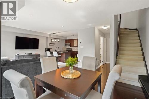 Open-concept living area featuring rich wood-finish flooring, recessed lighting, a modern kitchen with a breakfast bar, and a carpeted staircase with a wood handrail - 7 Sirente Drive Unit# 7, Hamilton, ON - Indoor Photo Showing Dining Room