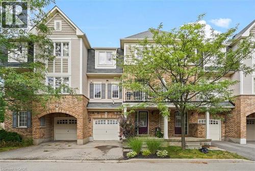 Multi-level townhome featuring brick and siding exterior, multiple gabled rooflines, a covered entry porch, and an arched garage entryway - 7 Sirente Drive Unit# 7, Hamilton, ON - Outdoor With Balcony With Facade