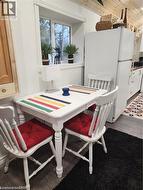 Dining area with white painted table, two white painted spindle-back chairs, and wood-finish flooring - 