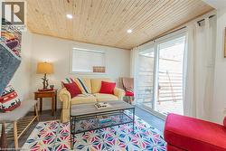 Living space featuring a natural wood plank ceiling with recessed lighting - 