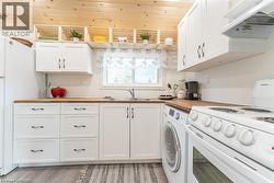 Kitchen featuring wood-finish countertops, white cabinetry with dark hardware, and a wood-paneled ceiling - 