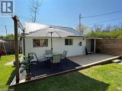 Rear exterior featuring a spacious wooden deck with integrated privacy screening, white horizontal siding, a sliding glass door, and a metal roof - 