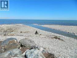 Stony beachfront with a clear water channel flowing into the expansive blue water - 