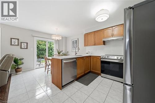Kitchen featuring wood cabinetry, stainless steel appliances, white tile flooring, and a sliding glass door - 200 Morrison Drive, Caledonia, ON - Indoor Photo Showing Kitchen