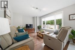 Living area featuring wood-finish flooring, light-toned walls, and a large window with white blinds - 