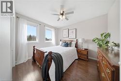 Bedroom featuring wood-finish flooring, light grey walls, and two large windows - 