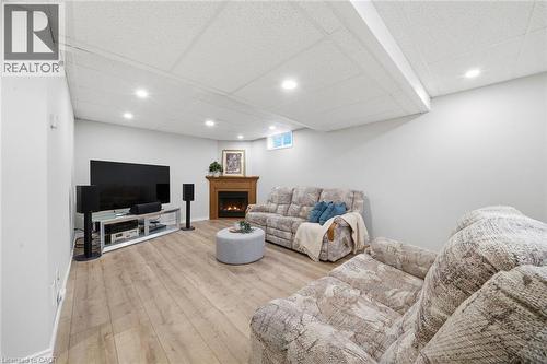 Spacious room featuring wood-finish flooring, a wood-surround fireplace, recessed ceiling lighting, and light gray wall finishes - 200 Morrison Drive, Caledonia, ON - Indoor Photo Showing Basement