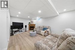 Spacious room featuring wood-finish flooring, a wood-surround fireplace, recessed ceiling lighting, and light gray wall finishes - 