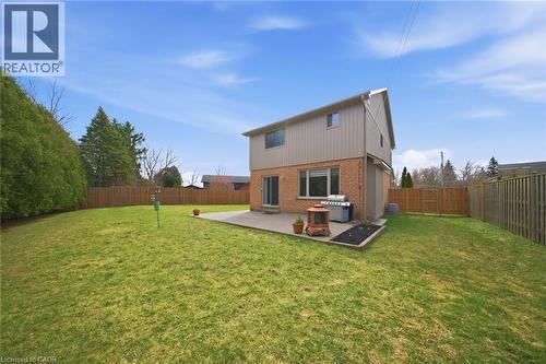 Expansive rear lawn framed by a wooden privacy fence and mature evergreen hedging - 200 Morrison Drive, Caledonia, ON - Outdoor With Backyard