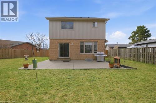 Expansive rear yard featuring a large concrete patio, privacy fencing, and a mature tree backdrop - 200 Morrison Drive, Caledonia, ON - Outdoor