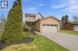Brick exterior with a peaked roofline, attached garage, concrete driveway, and front porch - 