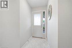 Entryway featuring a white door with decorative glass inserts, a full-length sidelight, and square tile flooring - 