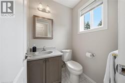 Bathroom featuring a single window, a vanity with a light-toned countertop and cabinet, an oval sink with a chrome faucet, and a wall-mounted light fixture - 
