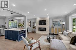 Open concept living space featuring a modern fireplace with a stacked stone surround, recessed lighting, and engineered hardwood flooring - 