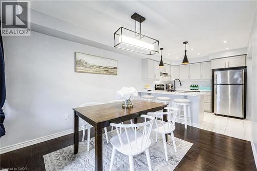 Open-concept kitchen and dining area featuring dark wood-finish flooring, light cabinetry, a white countertop, and stainless steel appliances - 1000 Asleton Boulevard Unit# 58, Milton, ON - Indoor Photo Showing Dining Room