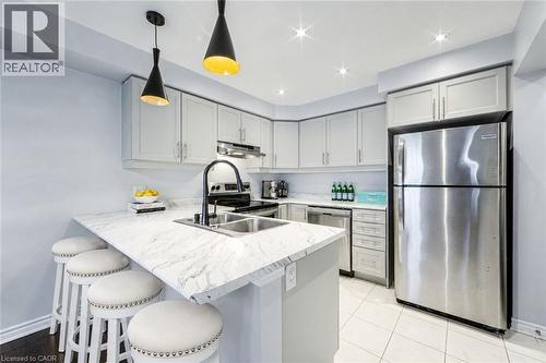 Kitchen featuring light grey cabinetry, stainless steel appliances, a double basin sink with a matte black faucet, and white countertop with veining - 1000 Asleton Boulevard Unit# 58, Milton, ON - Indoor Photo Showing Kitchen With Double Sink With Upgraded Kitchen