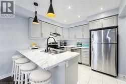 Kitchen featuring light grey cabinetry, stainless steel appliances, a double basin sink with a matte black faucet, and white countertop with veining - 