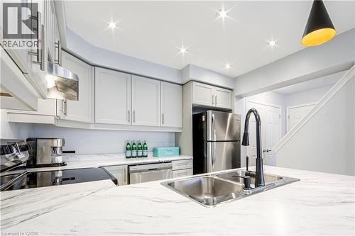 Kitchen featuring a double basin stainless steel sink with a matte black faucet, white countertops with veining, light gray cabinetry with brushed nickel hardware, and stainless steel appliances - 1000 Asleton Boulevard Unit# 58, Milton, ON - Indoor Photo Showing Kitchen With Double Sink
