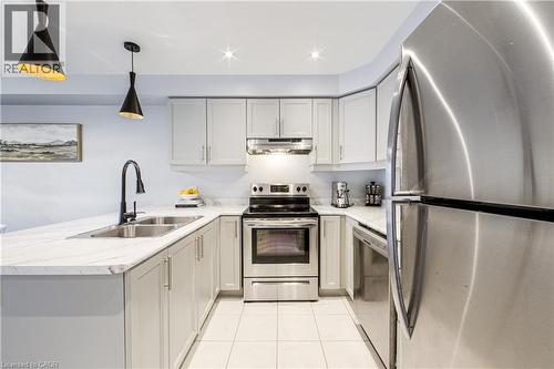 Kitchen featuring light gray cabinetry, stainless steel appliances, white patterned countertops, and a double basin sink with a matte black faucet - 1000 Asleton Boulevard Unit# 58, Milton, ON - Indoor Photo Showing Kitchen With Double Sink With Upgraded Kitchen