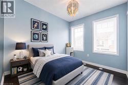 Bedroom featuring light blue walls and dark wood-finish flooring - 