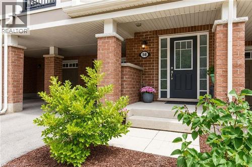 Brick facade with stone accents, a black entry door featuring a transom and sidelights, concrete steps, and a covered entry - 1000 Asleton Boulevard Unit# 58, Milton, ON - Outdoor With Exterior