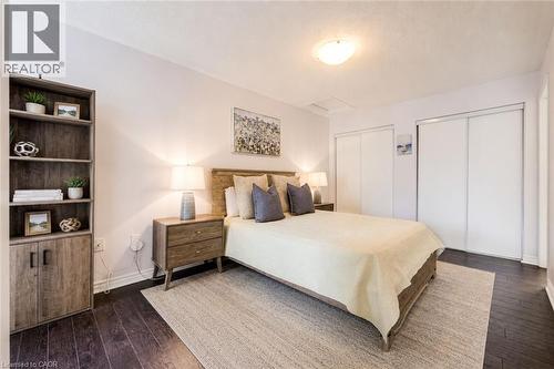 Dark wood-finish flooring complements light wall tones - 1000 Asleton Boulevard Unit# 58, Milton, ON - Indoor Photo Showing Bedroom