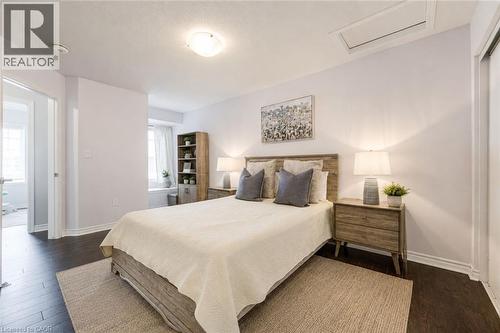 Bedroom featuring dark wood-finish flooring, light-colored walls, and a window with white curtains - 1000 Asleton Boulevard Unit# 58, Milton, ON - Indoor Photo Showing Bedroom