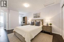 Bedroom featuring dark wood-finish flooring, light-colored walls, and a window with white curtains - 