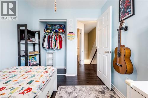 Bedroom featuring blue wall color, dark wood-finish flooring, and a built-in closet with shelving - 1000 Asleton Boulevard Unit# 58, Milton, ON - Indoor