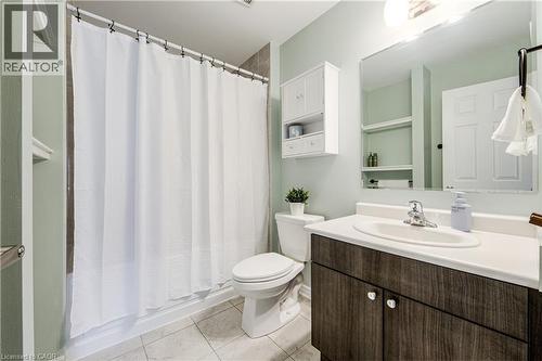 Bathroom featuring a wood-finish vanity with an integrated sink, white countertop, and tiled flooring - 1000 Asleton Boulevard Unit# 58, Milton, ON - Indoor Photo Showing Bathroom