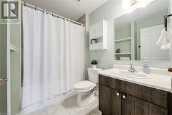 Bathroom featuring a wood-finish vanity with an integrated sink, white countertop, and tiled flooring - 