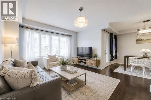 Open-concept living area featuring dark wood-finish flooring, a large bay window, and a contemporary chandelier - 1000 Asleton Boulevard Unit# 58, Milton, ON - Indoor Photo Showing Living Room