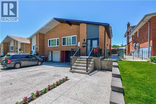 Brick exterior with a contemporary blue vertical siding accent, concrete driveway, and a front entry staircase with dark railings - 2560 Palisander Avenue, Mississauga, ON - Outdoor