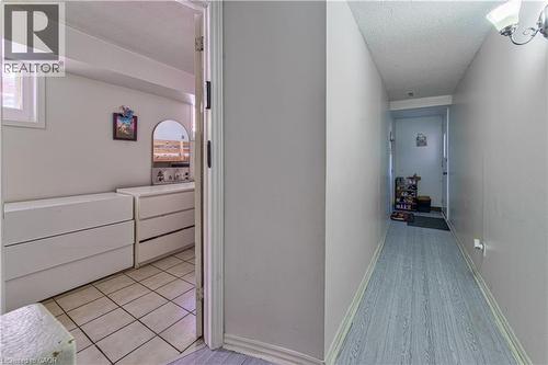 Hallway with light wood-finish flooring and a white door with dark hardware - 2560 Palisander Avenue, Mississauga, ON - Indoor Photo Showing Other Room