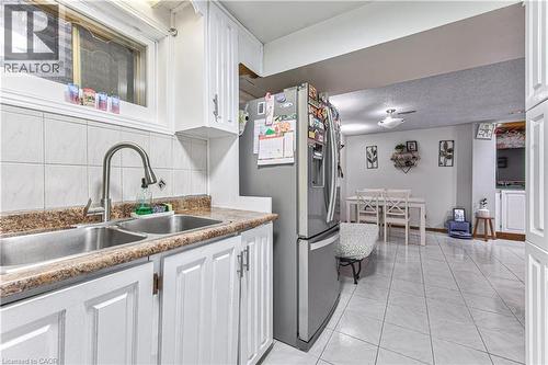 Kitchen featuring a stainless steel double basin sink with a high-arch faucet, white cabinetry, and granite-look countertops - 2560 Palisander Avenue, Mississauga, ON - Indoor Photo Showing Kitchen With Double Sink