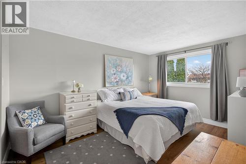 Bright bedroom featuring wood-finish flooring, light grey painted walls, and a large window with exterior views - 56 Brookstream Court, Hamilton, ON - Indoor Photo Showing Bedroom
