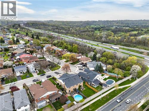Aerial perspective showcasing a residential area with varied home styles, tree-lined streets, and a prominent highway - 56 Brookstream Court, Hamilton, ON - Outdoor With View