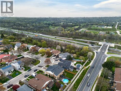 Aerial perspective showcasing a residential neighborhood with varied architectural styles, mature trees, and a highway running parallel - 56 Brookstream Court, Hamilton, ON - Outdoor With View