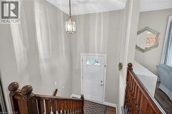Entryway featuring a white paneled door with an arched window, a brass lantern-style pendant light, and a dark wood banister - 