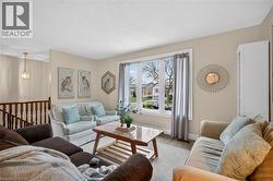 Bright living area with a large picture window, wood-finish flooring, and a built-in white cabinet - 