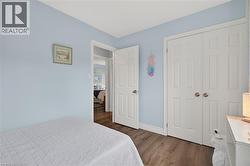 Bedroom featuring light blue walls, wood-finish flooring, white baseboards, and white bi-fold closet doors - 