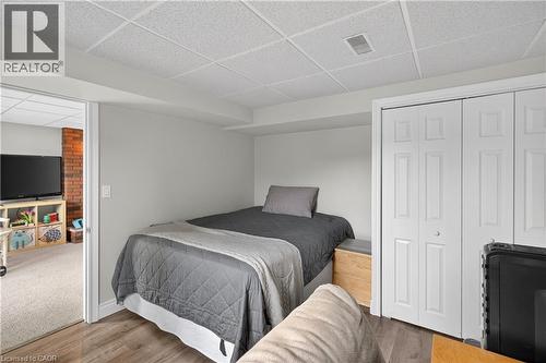 White bi-fold closet doors with panel detailing, wood-finish flooring, and a drop panel ceiling - 56 Brookstream Court, Hamilton, ON - Indoor Photo Showing Bedroom