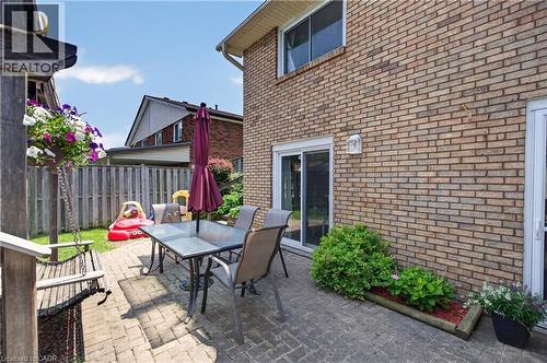 Patio area featuring brick paving, direct access to the interior via a sliding glass door, a brick exterior, a garden bed with plantings, and a wooden swing structure - 56 Brookstream Court, Hamilton, ON - Outdoor With Deck Patio Veranda With Exterior