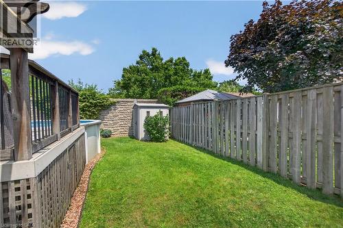 Spacious backyard featuring a manicured lawn, an above-ground pool with a surrounding wood-finish deck, a stone retaining wall, and a garden shed - 56 Brookstream Court, Hamilton, ON - Outdoor