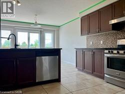 Kitchen featuring dark cabinetry, stainless steel appliances, a mosaic tile backsplash, and tile flooring - 