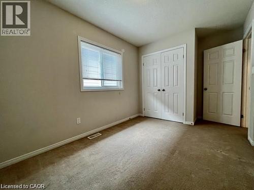 Carpeted room featuring a window with white blinds, a double-door closet with dark hardware, and a single paneled door - 300 Countrystone Crescent, Kitchener, ON - Indoor Photo Showing Other Room